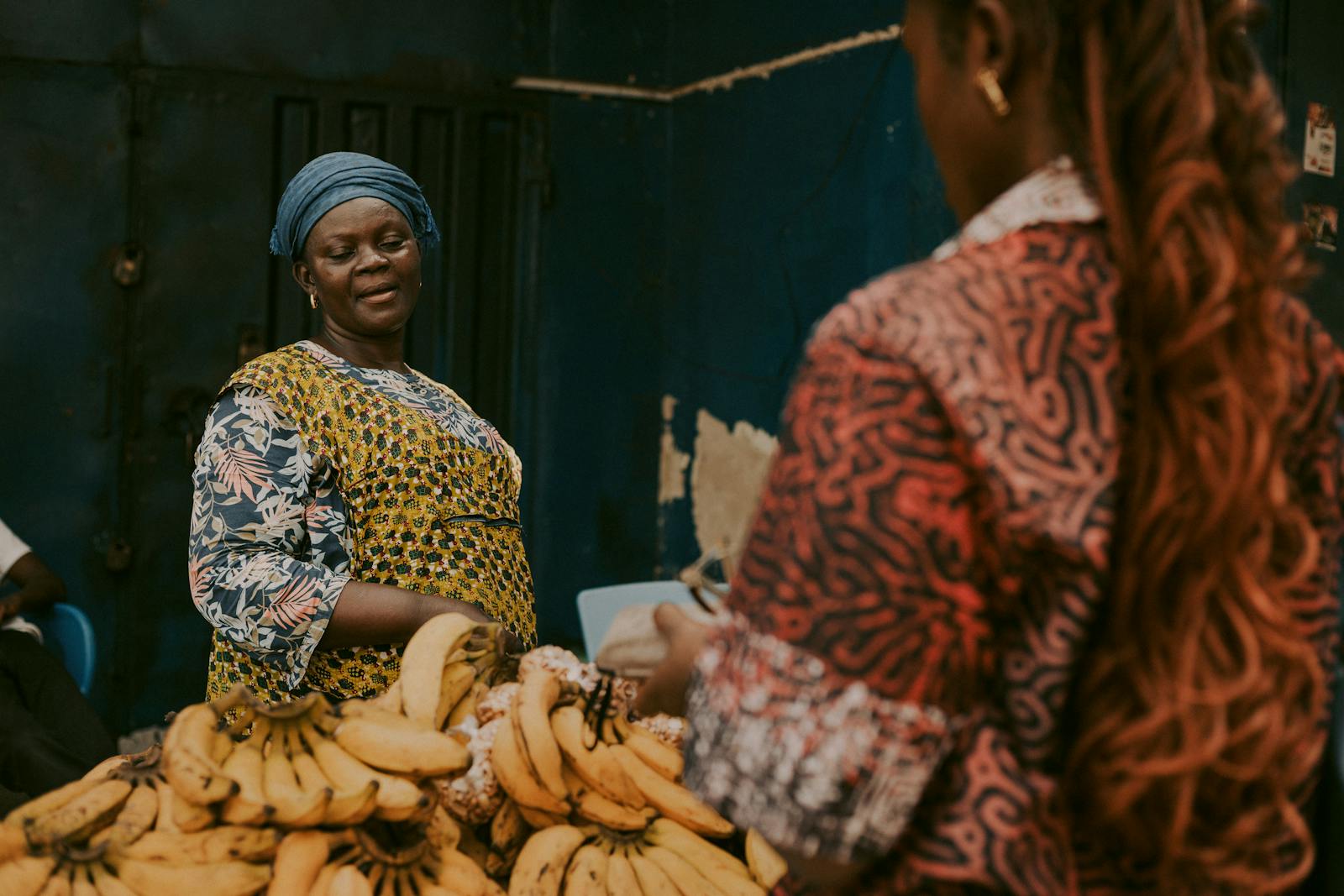 A vibrant African market scene showing a banana vendor interacting with a customer.