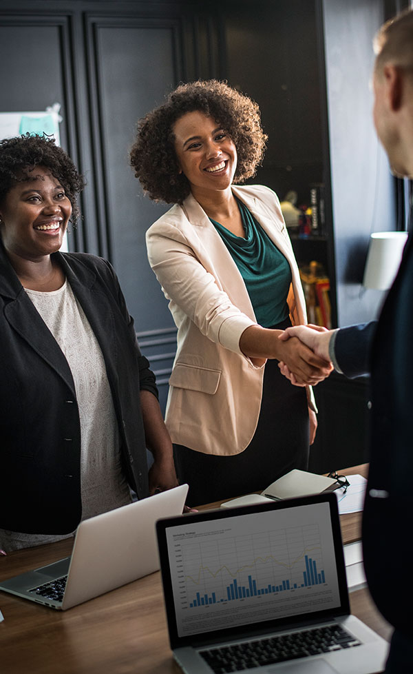 Two African women standing in an office smile at a man